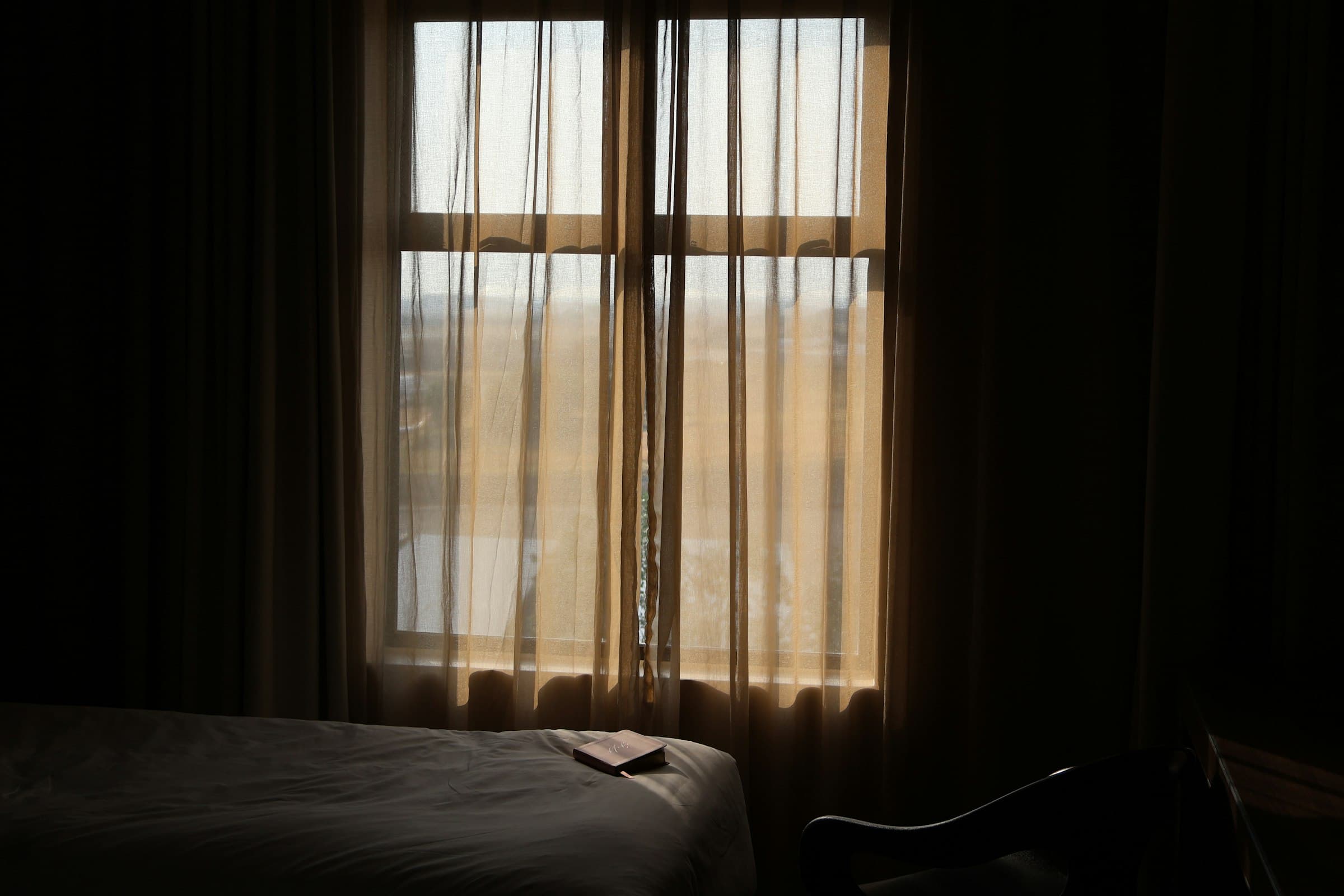 A dim hotel room, curtains drawn against the daylight