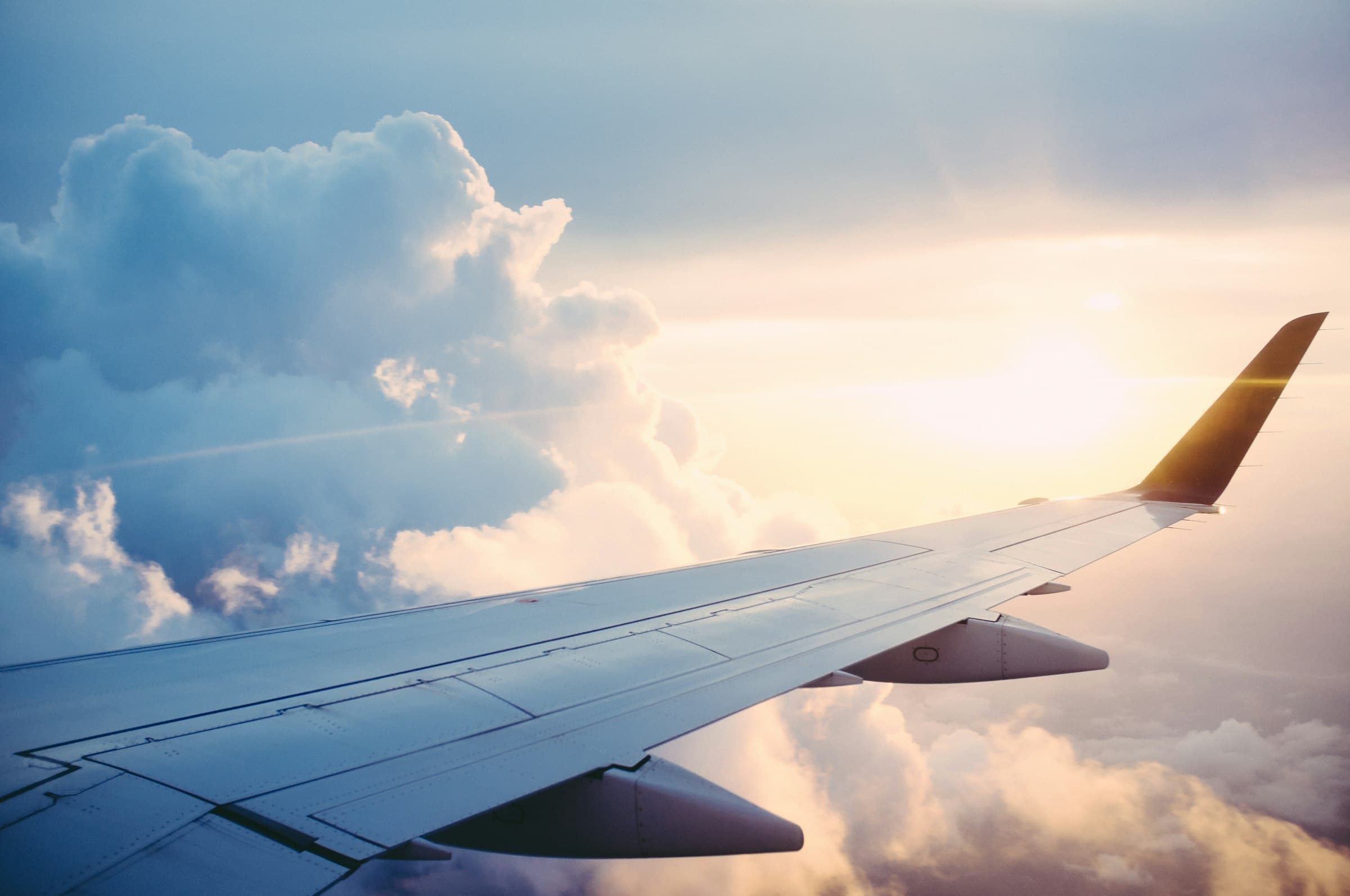 Aircraft wing over golden clouds at dusk